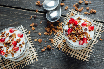Yogurt with granola in a glass on a wooden board 