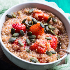 Quinoa porridge with strawberries and pumpkin seeds in bowl. Light dairy and gluten free breakfast