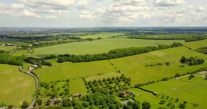 Panning aerial view of sittingbourne and maidstone road / dual carriageway and roundabout with green fields and blue sky in the background, Kent, England, UK