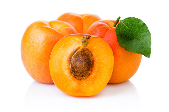 Ripe apricot fruits with with green leaf and slice isolated on white