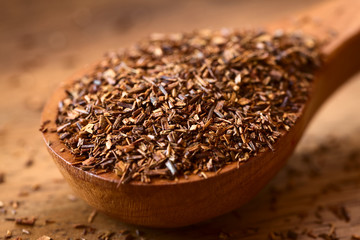 Rooibos herbal tea on wooden spoon, photographed on wood with natural light (Selective Focus, Focus...