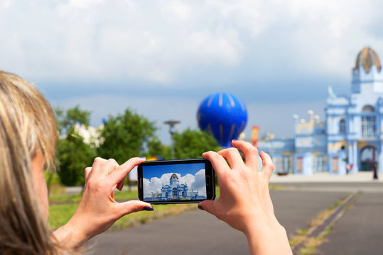 Woman tourist taking pictures on mobile phone of beautiful building