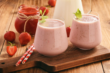 Healthy beverage-  strawberry milkshake in glasses on wooden background.