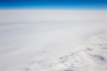 Above view of white clouds and a horizon with a blue sky.