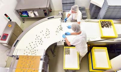 Lebensmittelindustrie: Arbeiter am Fliessband in der Produktion von Pralinen in einer Fabrik //...