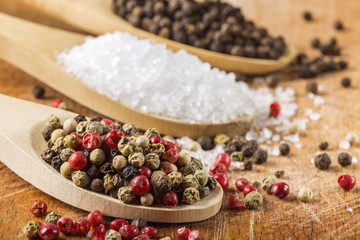 Wooden spoons with peppercorns and sea salt on wood