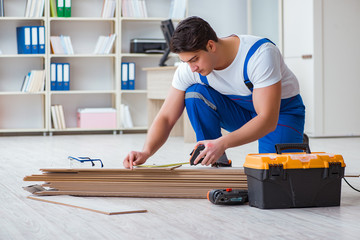 Young worker working on floor laminate tiles