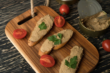 Liver pate on the bread on wooden tray.