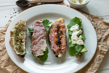 Open sandwiches with different components on a white plate
