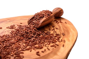Gray rice on an olive board with a wooden scoop isolated on a white background