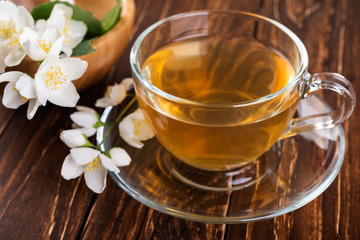 Jasmine tea with jasmine flowers on a rustic wooden  background.