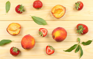 peach fruit with strawberry and green leaf on light wooden background. top view with copy space