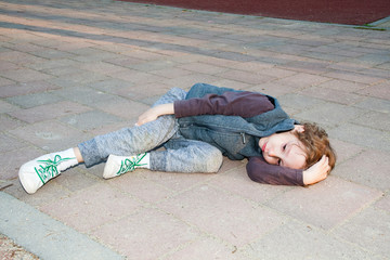 Sad boy with broken leg after running in park. Little child crying while holding his leg after...
