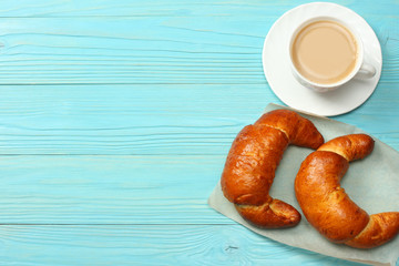 Coffee background. Cup of coffee with croissant and coffee beans on blue wooden background. Top view with copy space.