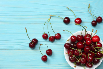 cherries in bowl on blue wooden background. Top view with copy space.