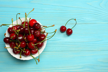 Fototapeta na wymiar Cherry on plate on blue wood background. top view with copy space