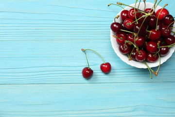 Obraz na płótnie Canvas cherries in bowl on blue wooden background. Top view with copy space.