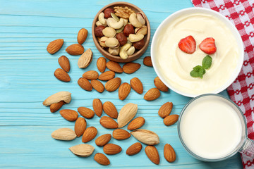 Milk background. Glass jug pitcher of fresh milk with glass, mix almonds, cashew nuts, hazelnut, peanuts, walnuts, pistachio on blue wooden background. Top view with copy space.