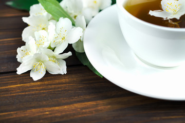 Obraz na płótnie Canvas Tea with jasmine in a white cup on a wooden table.