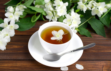 Tea with jasmine in a white cup on a wooden table.