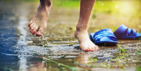 Bare Feet of Child Jumping into Rain Puddle Playful Moment Scene