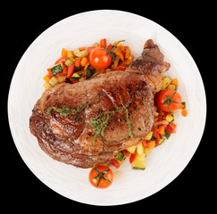 Tasty ribeye steak with stir fried vegetables isolated on black
