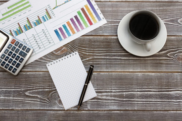 Business idea concept. Notebook and coffee, printout of the profit growth graph, calculator. Against the background of a natural wood texture.