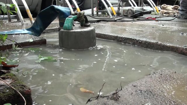 Workers are emptying the water left on the ground after a water leak, they use a pump to empty the water.