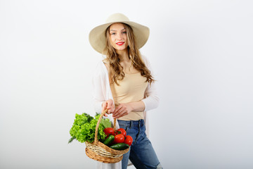 Young woman with a wicker basket of healthy food, vegetables, on white background, copy space