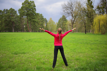 Woman standing back full lenght in green fresh park with hands up, copy space, space, nature