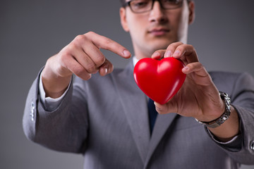 Businessman holding red heart in love concept