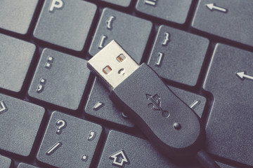 Usb cable connector on a black laptop keyboard close up. Toned image