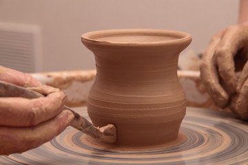 Hands of a potter, creating an earthen jar on pottery wheel.