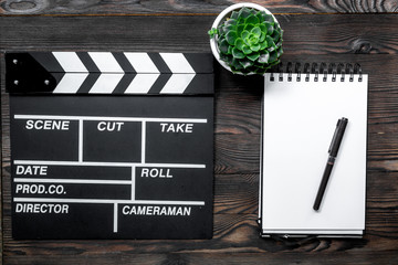 Work table of producer. Movie clapperboard and notebook on wooden table background top view