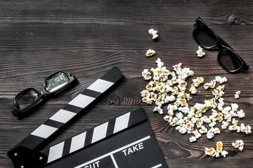 Watching the film. Movie clapperboard, sunglasses and popcorn on wooden table background top view...