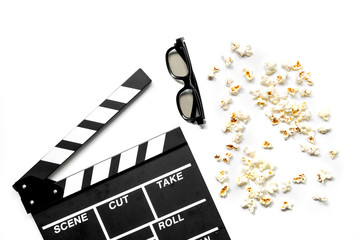 Watching the film. Movie clapperboard, sunglasses and popcorn on white background top view