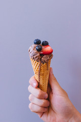 Hands holding chocolate ice-cream with blueberry and strawberry