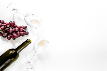 Obraz premium Composition with bottle of red wine, wineglasses and red grape on white background copyspace top view