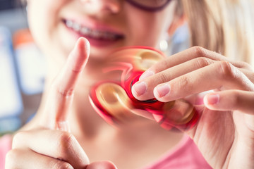 Fidget Spinner. Cute young girl playing with fidget spinner. - obrazy, fototapety, plakaty