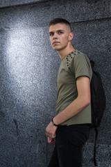 Handsome man on the background of a granite wall in a public place, teenager