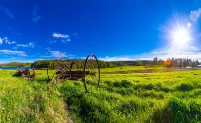 Old farm equipment on field background.