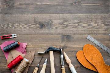 Set of cobbler tools on brown wooden desk background top view copyspace