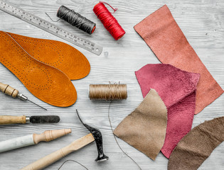 Working place of shoemaker. Skin and tools on grey wooden desk background top view