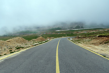 Asphalt road into misty mountains