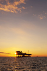 An offshore oil installation and a platform supply ship at sunset time 