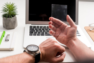 Businessman is sitting at table and holding futuristic gadget