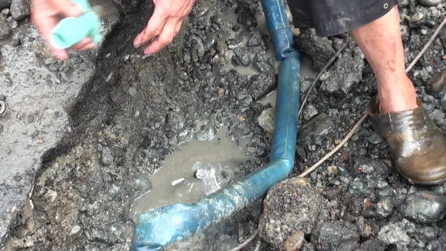 A worker is repairing with his hands a pipe that is broken on a road in Taipei, capital of Taiwan.