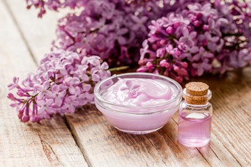 Fototapeta na wymiar take bath with lilac cosmetic set and blossom on wooden table background