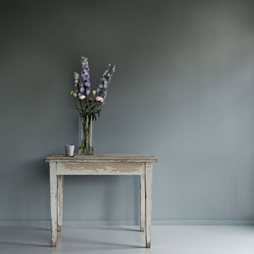 Vase and coffee cup on wooden table against gray wall
