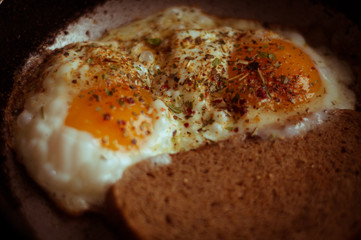 Fried eggs with bread in a frying pan and sprinkled with seasoning